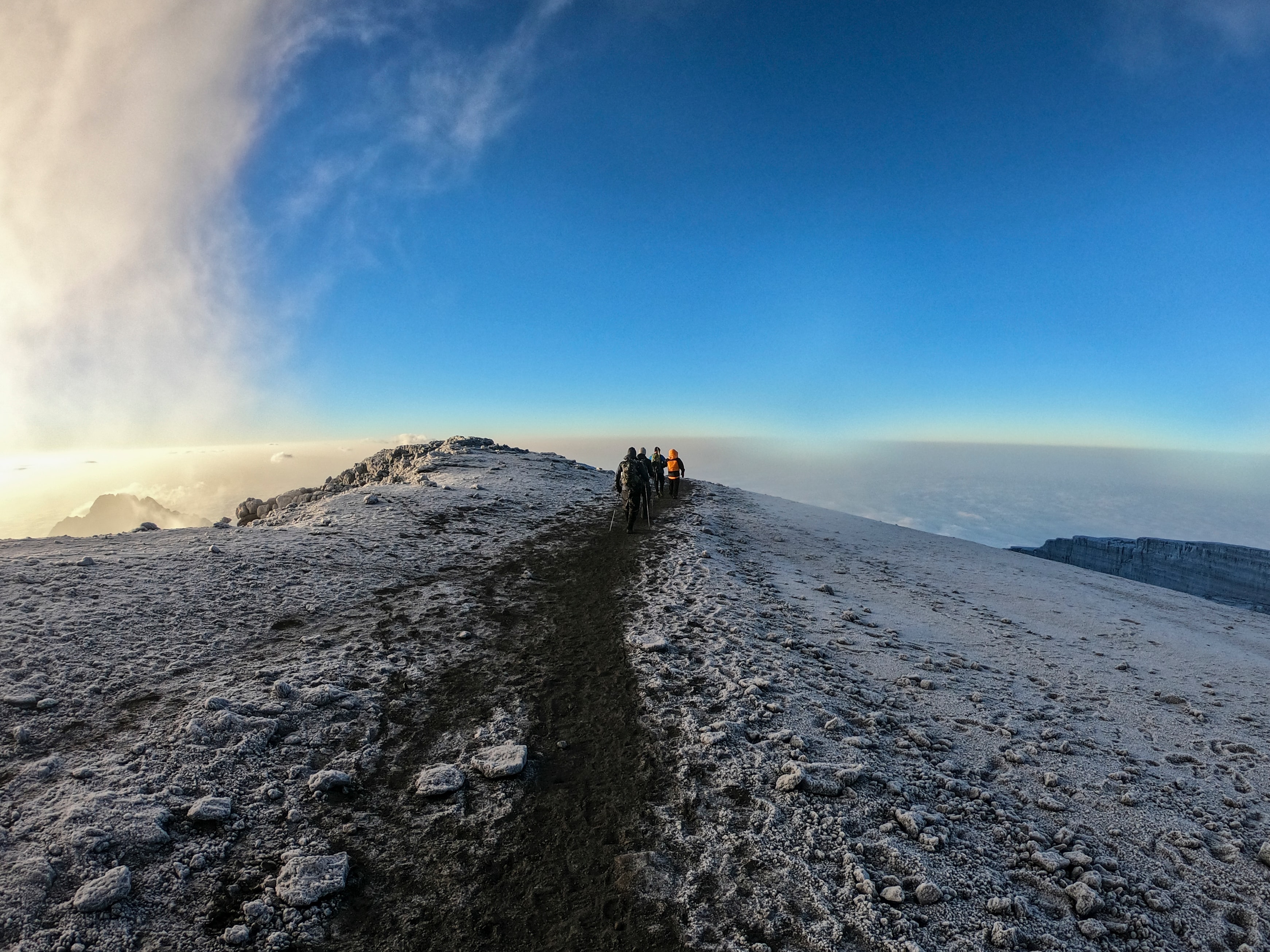 A line of hikers trekking down the steep, loose scree slope from Stella Point on Mount Kilimanjaro.