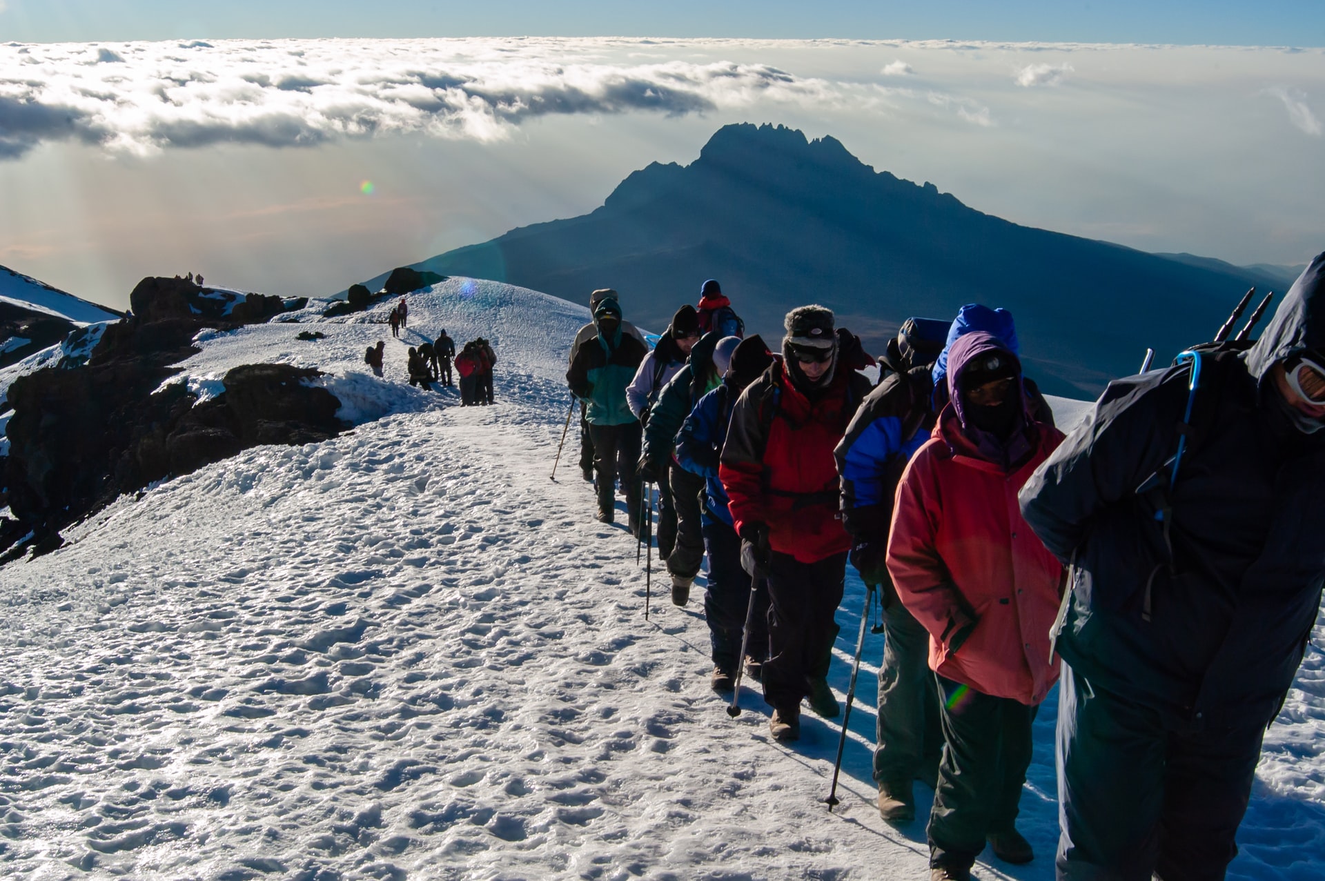 A determined group of mountaineers walking along the snowy crater rim, just 500 meters from Uhuru Peak.