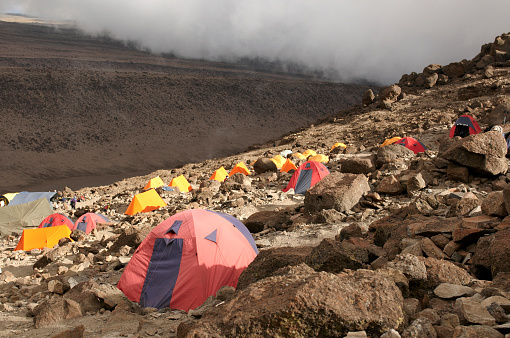 A vibrant cluster of colorful expedition tents pitched across the rugged, rocky terrain of Karanga Camp on Mount Kilimanjaro.