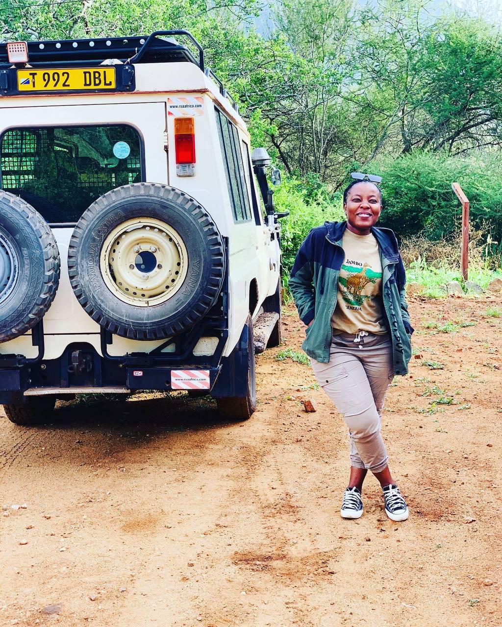 A professional and welcoming portrait of Tina, the founder and director of Moipo Adventures, smiling against a scenic Tanzanian backdrop.